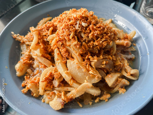 Close up of Thai style stir-fried [pork] heavily topped with crispy fried garlic on a plate. Traditional Asian food.