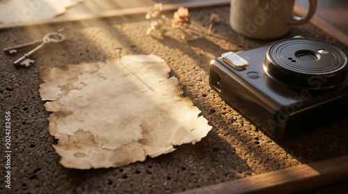 Vintage camera and old parchment paper on textured wooden surface with warm sunlight creating nostalgic atmosphere
