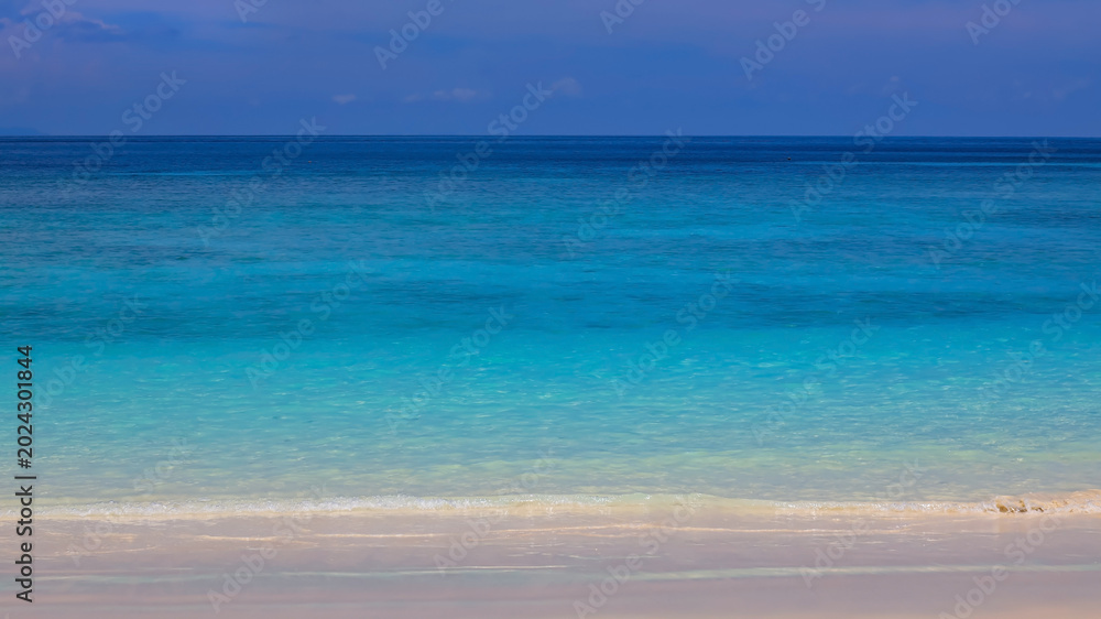 Fototapeta premium The background for summer vacation concept with the nature of clear water sea beach and summer with sunlight, sandy beach as The sparkling sea water contrasts with the blue sky