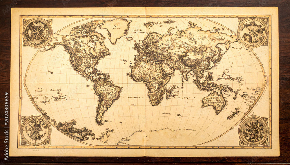 Fototapeta premium Antique world map on aged parchment over dark wood. This retro cartography piece symbolizes global exploration and history, ideal for travel, adventure, and educational storytelling.