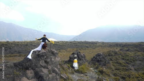 Traditional Balinese dancer performing on a rocky hill with mountain views in 4K.