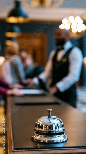 Luxury hotel reception bell on elegant counter with blurred concierge background symbolizing hospitality, service and premium travel experience.