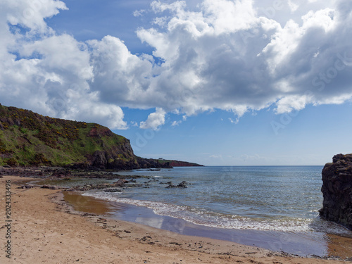 фотографія A small deserted bay between the rocks at the northern end of St Cyrus Beach with the calm water receding with the tide