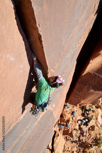 Fotografie Climber battling crack on sandstone cliff in indian creek