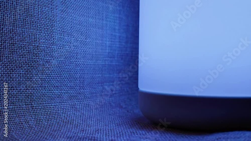 A close-up of a teal-colored object with a black base on a textured surface