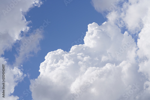 Photography Large white clouds gather in bright blue sky with sunlight shining during daytim