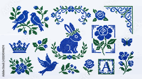 Blue and green embroidery patterns with birds, rabbit and floral motifs in a traditional cross-stitch style, provides decorative elements for textile design and illustrating folk art aesthetics