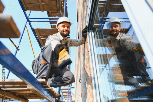 Tableau sur toile Construction worker installing window on building facade