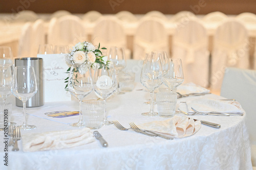 Elegant table setting with white tablecloth and floral centerpiece at an event