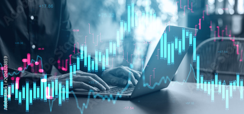 Canvastavla Hands typing on laptop with glowing candlestick chart overlay showing financial market activity and volatility in modern business environment