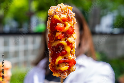 Close Up of Korean Gamja Hot Dog with Blurred Person Background