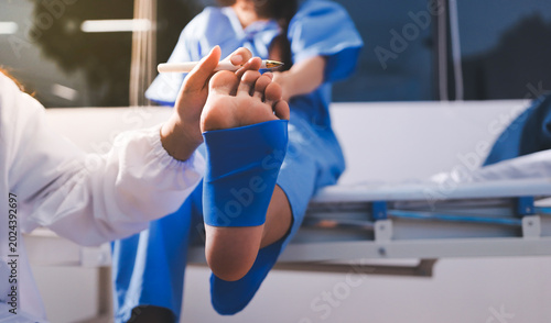 Doctor checks Asian senior woman patient after knee replacement operation in hospital room. Nurse examines leg after surgery. Medicine health treatment therapy healthcare concept