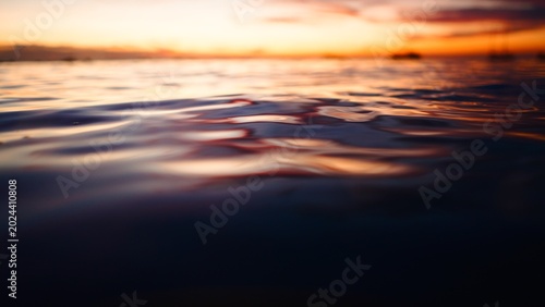 Fotografie Reflecting vibrant sunset hues on ocean surface creating ripple patterns at dusk