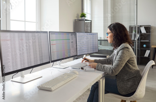 Accountant analyst works on computer monitors spreadsheets. In an office, the woman auditor reconciles finance, checks data quality, and runs analytics. Business accuracy and control concept.