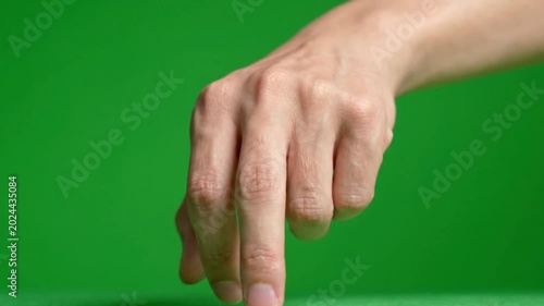 Close-up of a person's hand gesturing against a green background