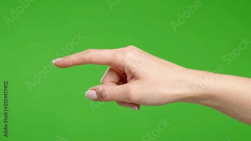 Graceful female hand making a pointing gesture or interacting with an unseen element, isolated on a chroma key green studio background