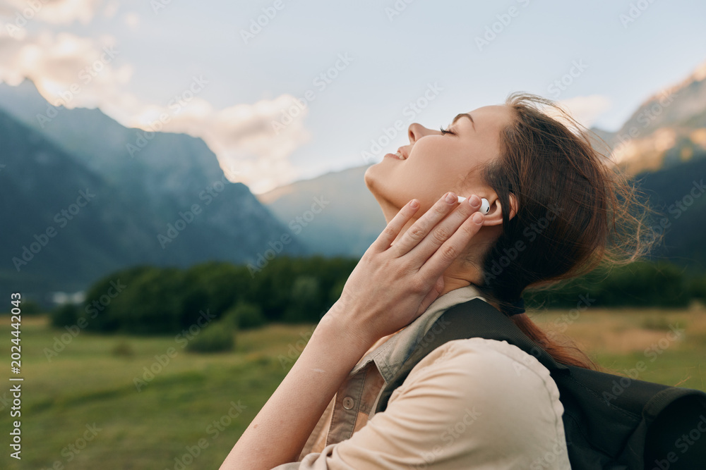 Fototapeta premium A woman enjoys the outdoors in a mountain landscape, head tilted back to feel the breeze in bright open air. A serene moment of nature, calm and breathing freely.