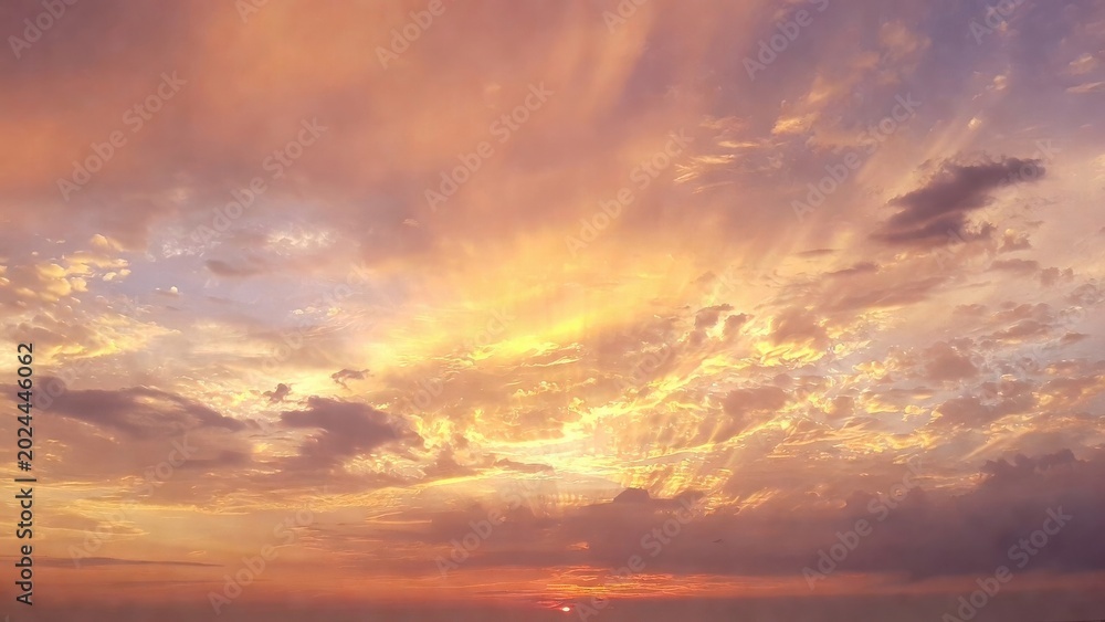 Fototapeta premium Dramatic sunrise over ocean with golden clouds and soft light landscape scenery