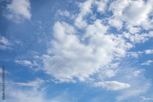 Fotografie White fluffy clouds scattered across the vibrant blue sky creating a beautiful natural texture