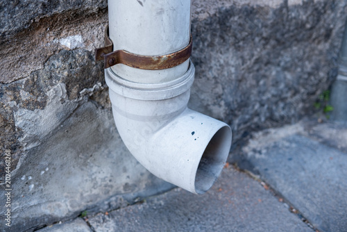 Quadro em tela White plastic drainpipe fixing to a weathered stone wall, showing a rusted metal