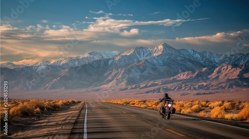 Motorcyclist riding on road towards majestic mountains under a dramatic sky