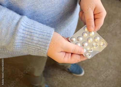 Tableau sur toile Looking down holding a pill. Antidepressant and antipsychotic.