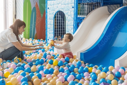 Mother and toddler playing together in colorful ball pit playground