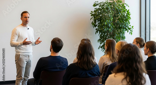 A man in a white sweater lectures to an audience seated in chairs, symbolizing education, presentation, and knowledge sharing, ideal for business or conference themes