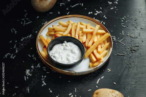 Slika na platnu Crispy fries with creamy dip on textured plate