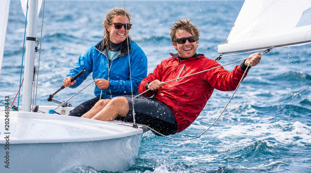 Obraz premium Young couple sailing together, enjoying the moment on the water with bright smiles