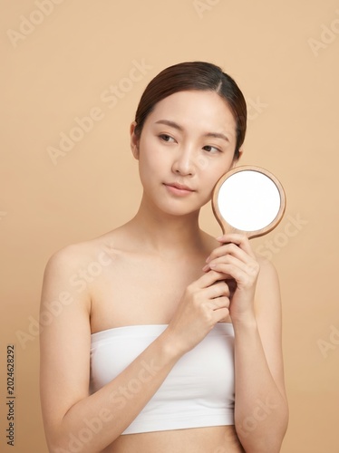 Young asian woman holding a small hand mirror