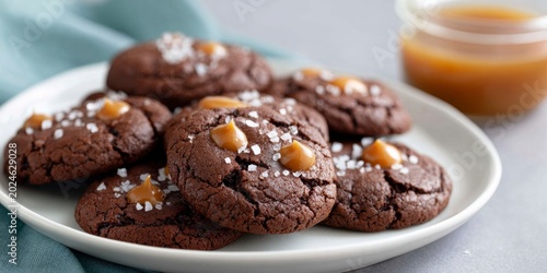 a plate of chocolate cookies with caramel drops and sea salt on top