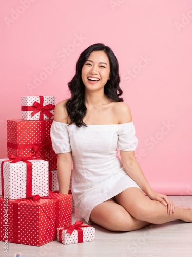 Happy young woman sitting with many red gift boxes