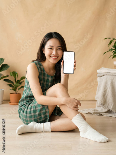 Happy young woman showing smartphone screen in bright room