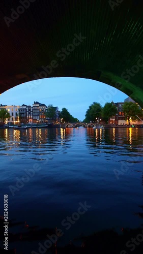 Immersive POV boat ride through
Amsterdam canals passing under illuminated brick arch bridge at night