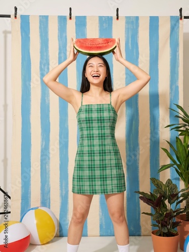 Happy young woman holding watermelon slice on her head