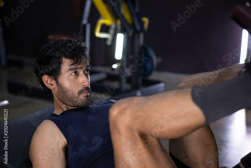 Φωτογραφία Young man performing fitness gym leg press exercise with focused determined expr