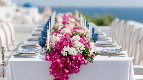 Bright Mediterranean style celebration table with vibrant pink flowers and elegant coastal decor overlooking the sea