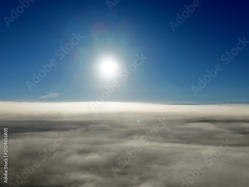 Cuadro en lienzo defaultFotografia aérea capturada por drone mostrando um mar de nuvens brancas sob um céu azul limpo com o sol brilhando intensamente ao centro