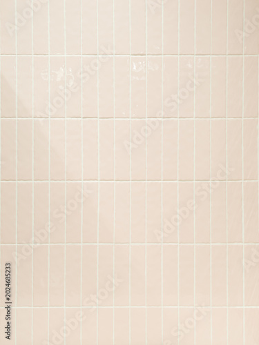 Glossy pastel pink ceramic tile wall with square grid pattern, soft reflections and minimal aesthetic background, ideal for interior design, bathroom or trendy backdrop.