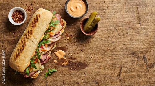 Gourmet sub sandwich top view food photography with ingredients on rustic wooden background