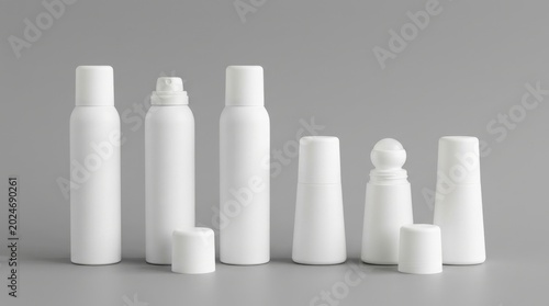 Collection of assorted white aerosol cans and bottles with caps on a gray background, container