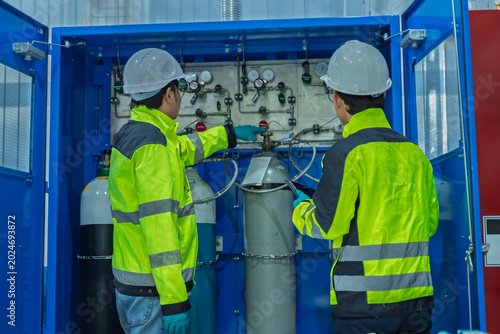 Bild auf Leinwand Two Asian engineers inspecting industrial gas manifold system