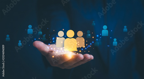 Hand holding illuminated group of people icons with glowing light effect.
