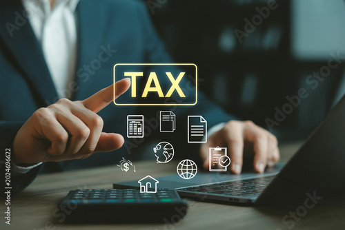Businessman pointing at tax text icon while using laptop and calculator.