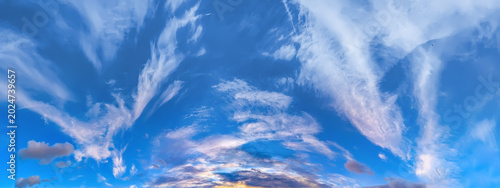 Colorful evening sky at sunset. Flattened flakes of cloud against blue sky. The sun's farewell is exploding to two fun to horizon. A serene landscape of peace and elemental energies.