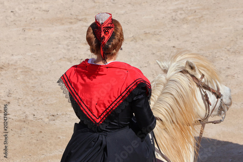 Photos Une arlésienne de dos  en costume sur un cheval de Camargue