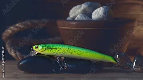Obraz na plátne Green fishing lure wobbler with sharp hooks on a rustic wooden background