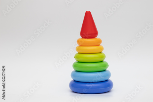 Colorful rainbow stacking toy pyramid with plastic rings on white background