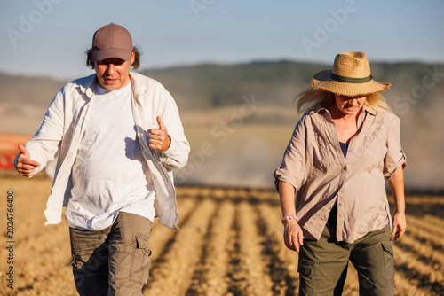Farmer and agronomist discussing agricultural activity and work on cultivated field. Teamwork in agriculture